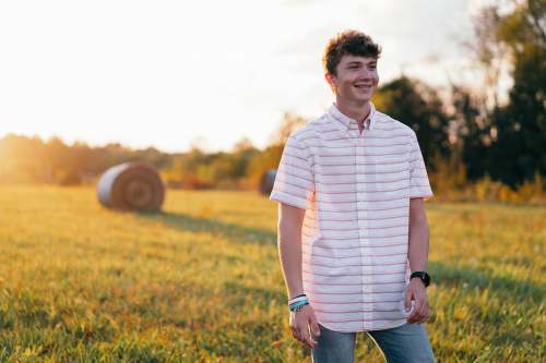 united states man in white and black stripe polo shirt standing on green grass field during daytime field